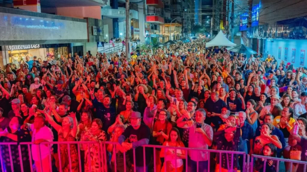 Festival de Inverno de Guarapari 2025: Destaques da Primeira Noite e Guia Completo 2 Grande público reunido, com mãos levantadas e sorrisos, apreciando a programação noturna do Festival de Inverno de Guarapari 2025.
