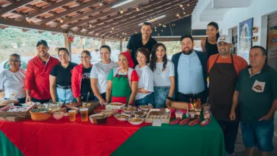 Grupo de moradores e cozinheiros sorrindo atrás de mesa com pratos típicos italianos em Buenos Aires, Guarapari