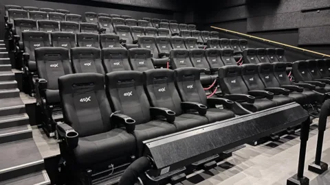 Fileiras de poltronas pretas em uma sala de cinema