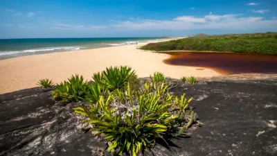 Lagoa de Caraís, de águas avermelhadas, ao lado da praia no Parque Estadual Paulo César Vinha