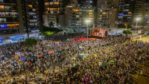 Multidão reunida diante de palco iluminado na virada do ano em Guarapari
